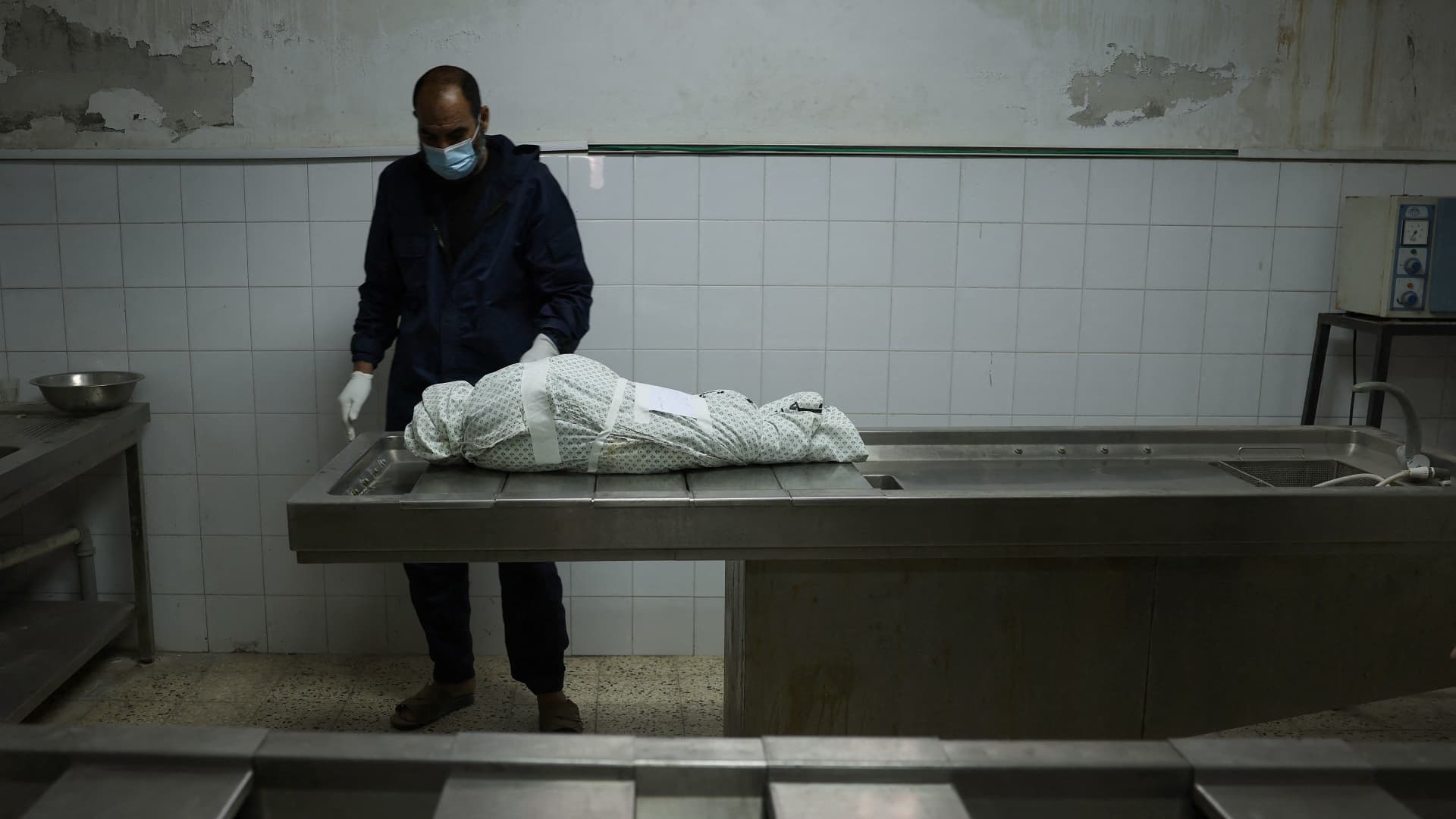 A Palestinian man stands by the body of Menna Shreir, 3, on May 19, 2021 at a morgue in Gaza City, after she died of her injuries following an Israeli air strike.