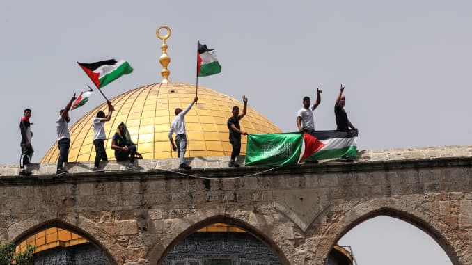 Palestinians hold flags as they stand at the compound that houses Al-Aqsa Mosque, known to Muslims as Noble Sanctuary and to Jews as Temple Mount, in Jerusalem's Old City May 21, 2021.