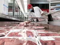A butcher stocks a display case with packages of steaks at a Costco store on May 24, 2021 in Novato, California.