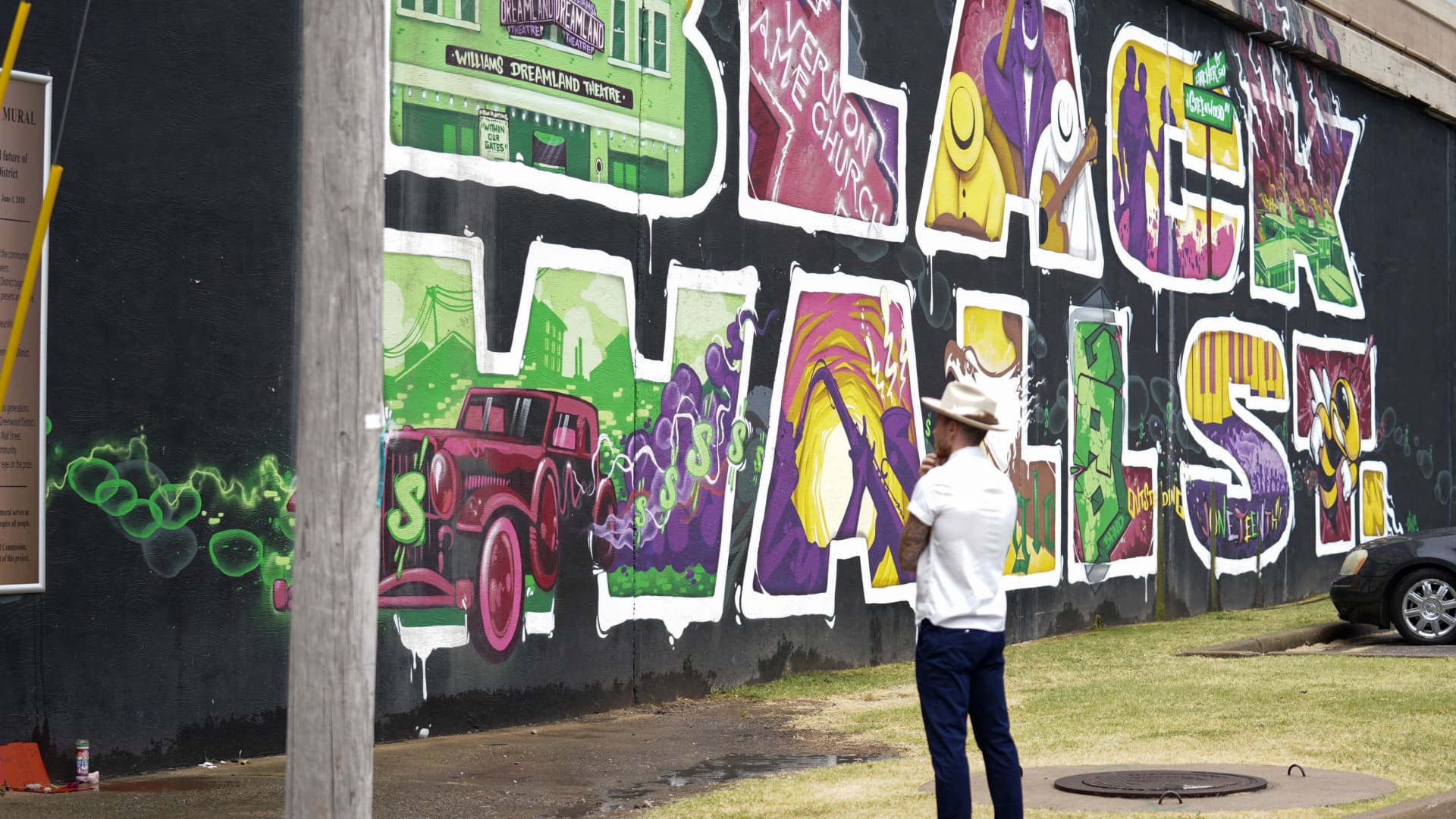 A pedestrian stands in front of the Black Wall Street Mural in the Greenwood District of Tulsa Oklahoma, U.S., on Friday, June 19, 2020.