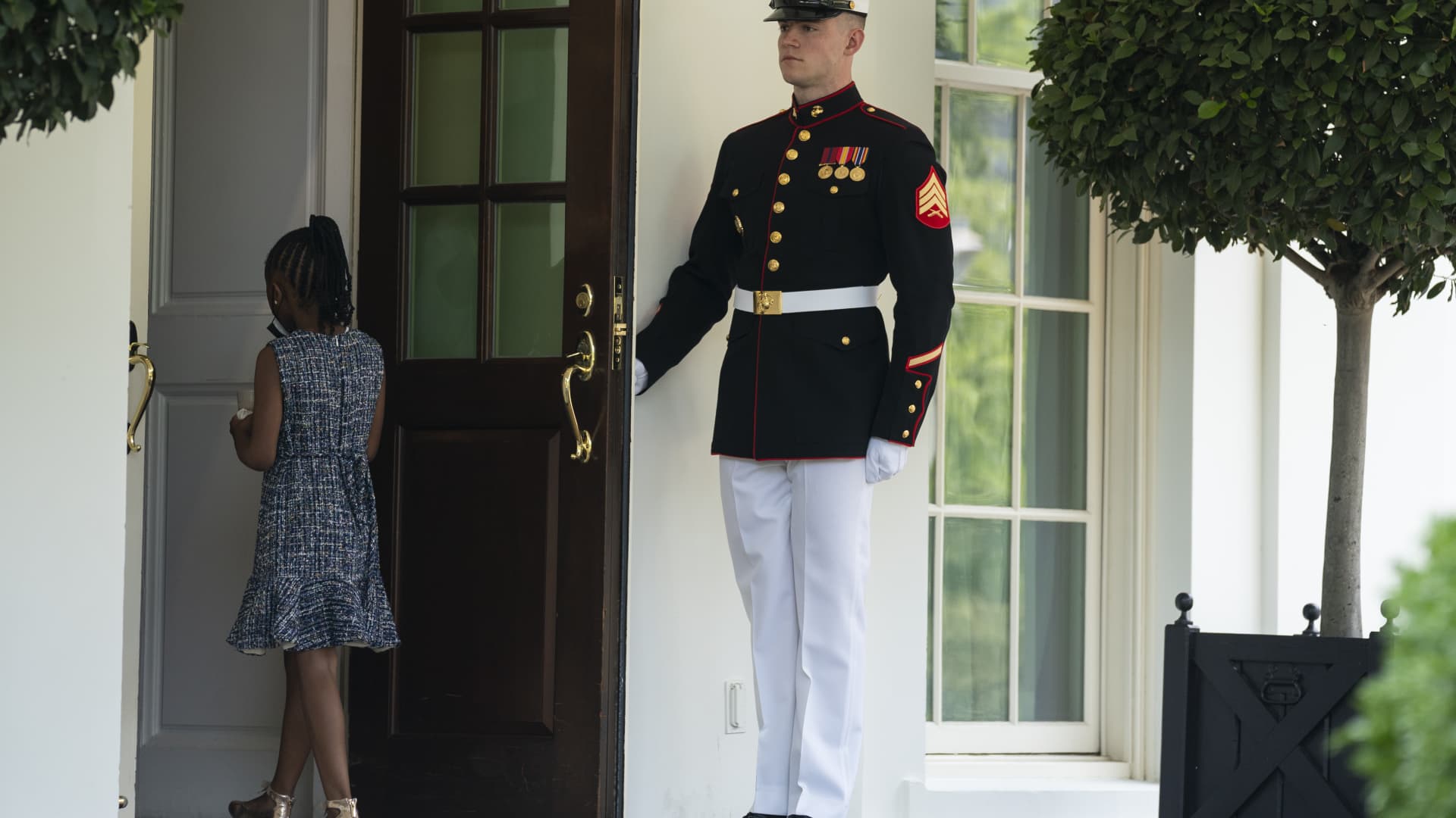 A Marine holds the door as Gianna Floyd, the daughter of George Floyd, walks into the White House, Tuesday, May 25, 2021, in Washington.