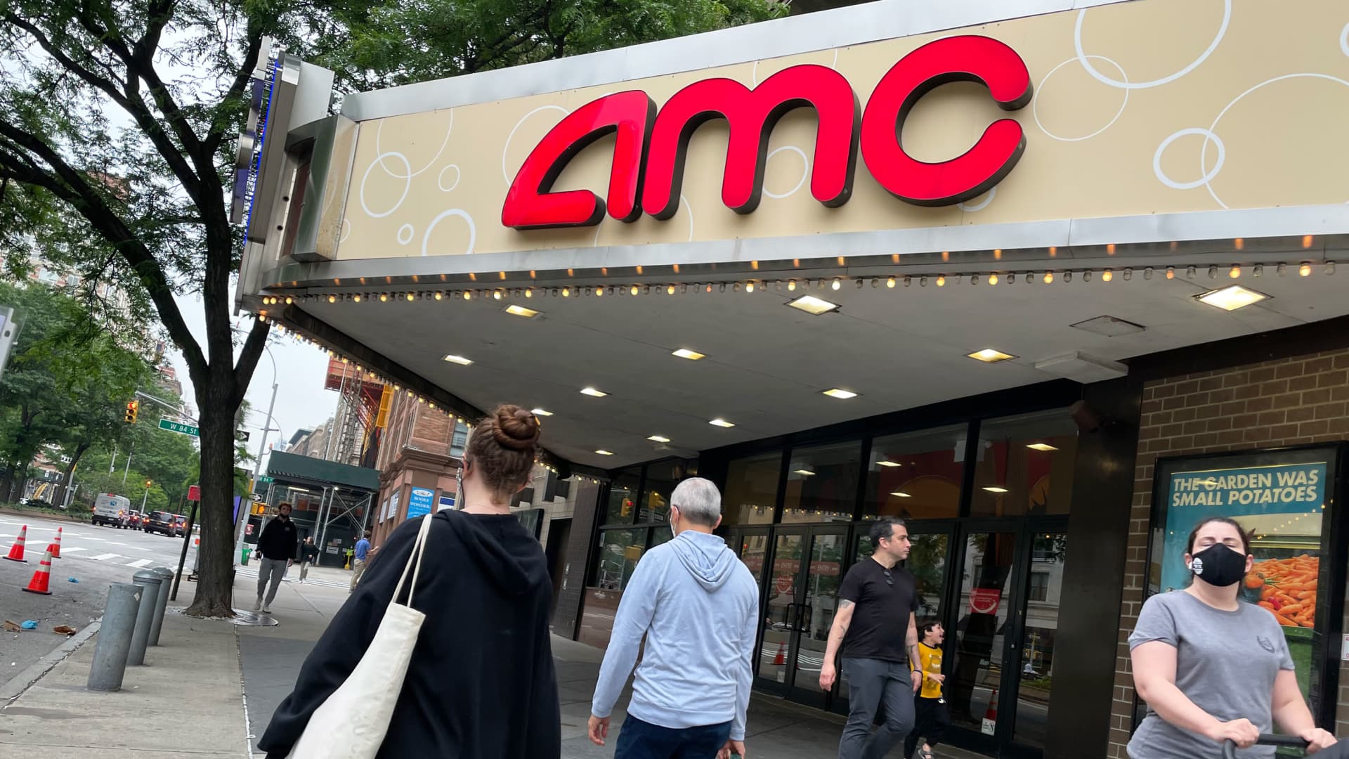 Pedestrians pass in front of an AMC theater in New York.