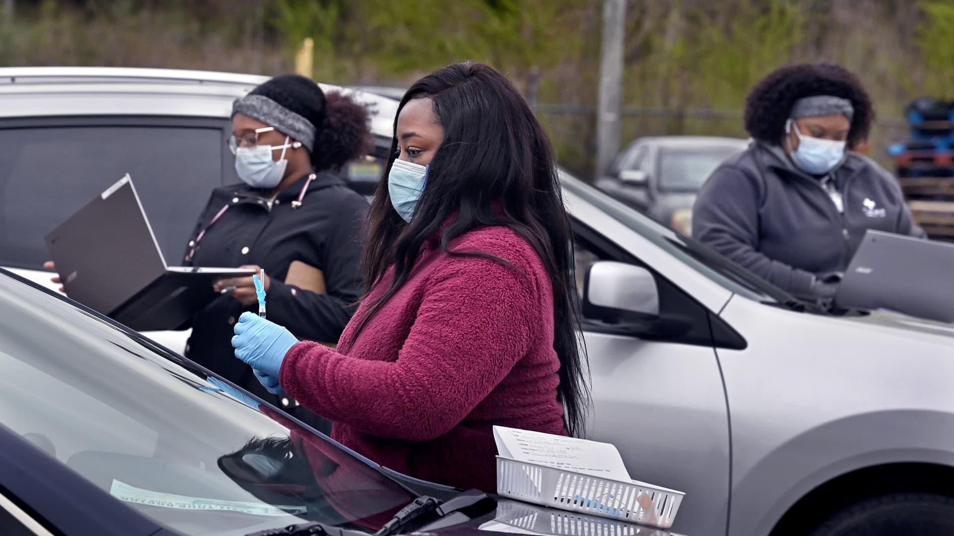 Lashondra Walter, (center), a nurse practitioner for Cahaba Medical Care gets ready to give a shot to a person in their car. She was joined by colleagues who roamed the parking lot with laptops to register people at the Linden National Guard Armory in Linden, Alabama on Friday, March 19, 2021.