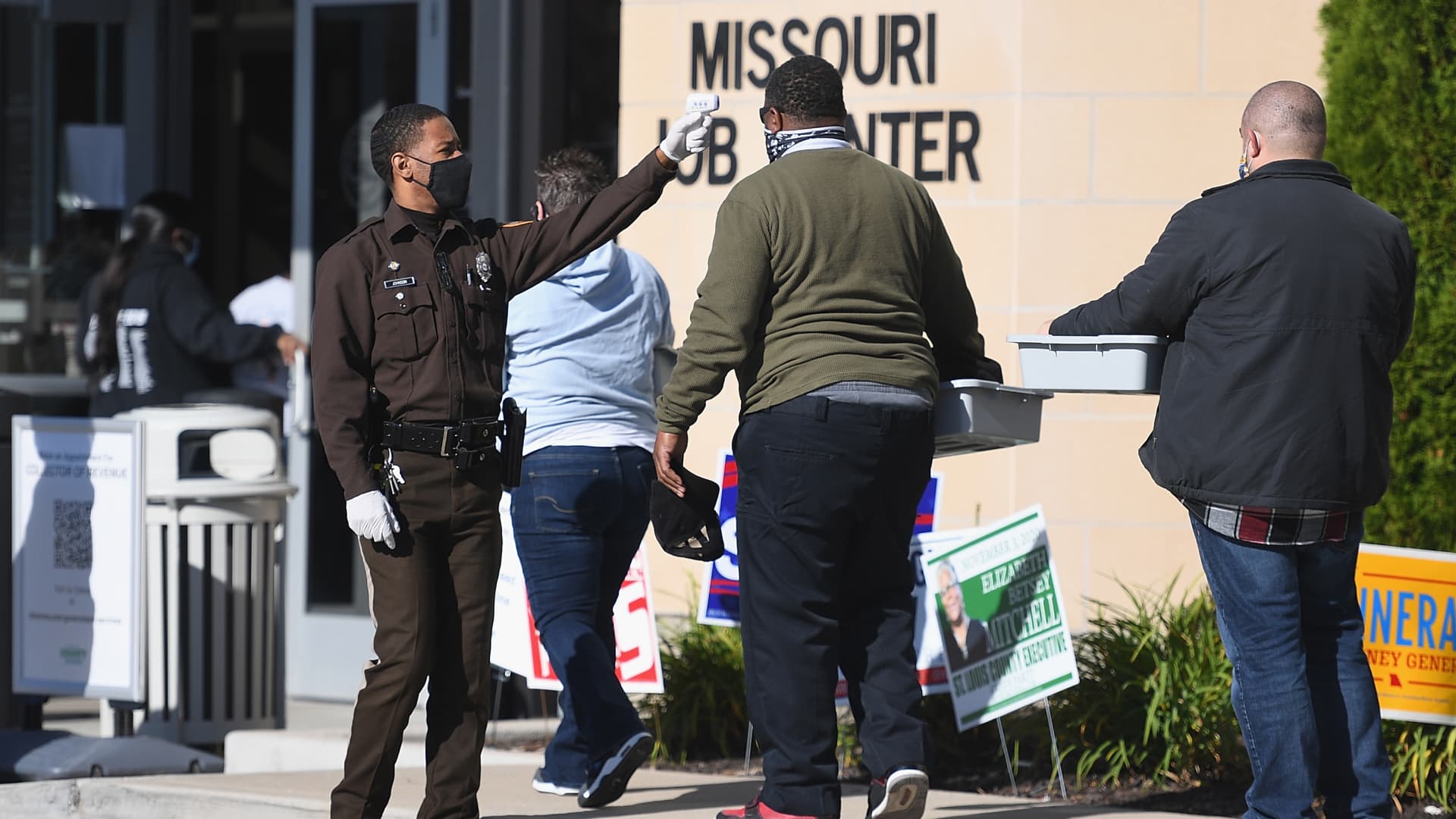 A Law Enforcement Officer temperature screens voters as they wait in line to cast their ballots on November 3, 2020 at the St. Louis County Board of Elections in St. Ann, Missouri.
