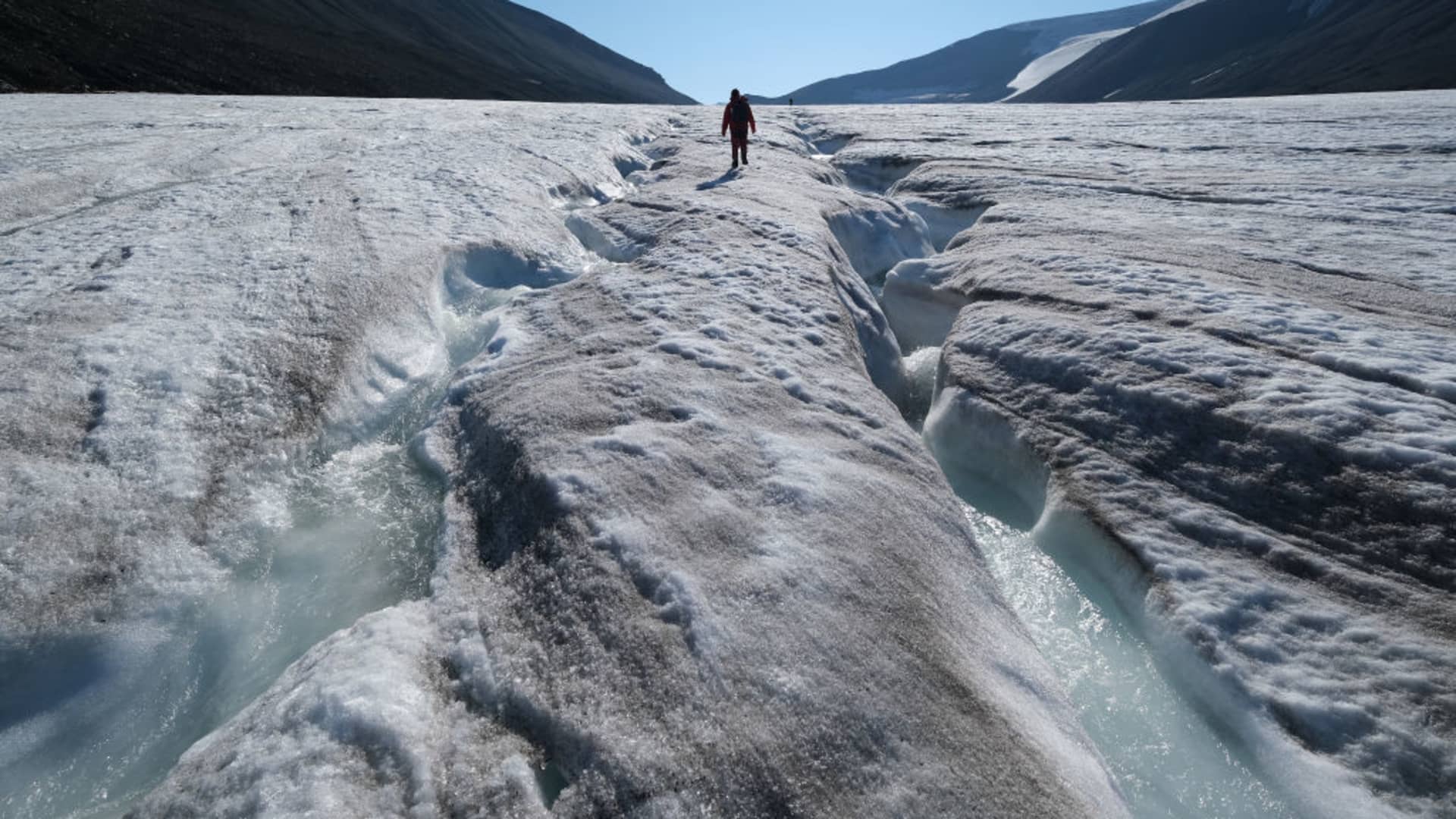 A hiker walks among winding channels carved by water on the surface of the melting Longyearbreen glacier during a summer heat wave on Svalbard archipelago on July 31, 2020 near Longyearbyen, Norway. Global warming is having a dramatic impact on Svalbard that, according to Norwegian meteorological data, includes a rise in average winter temperatures of 10 degrees Celsius over the past 30 years, creating disruptions to the entire local ecosystem.