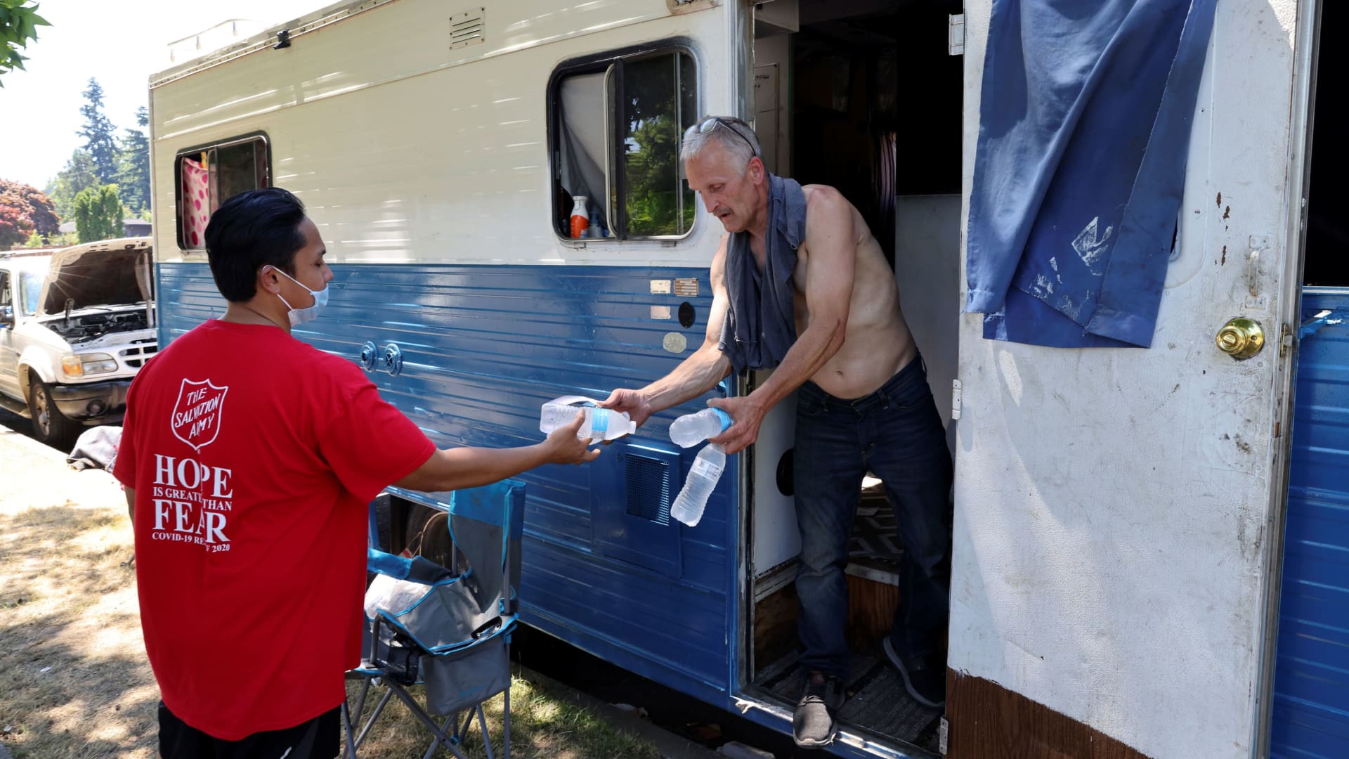Shanton Alcaraz from the Salvation Army Northwest Division gives bottled water to Eddy Norby who lives in an RV and invites him to their nearby cooling center for food and beverages during a heat wave in Seattle, Washington, U.S., June 27, 2021.