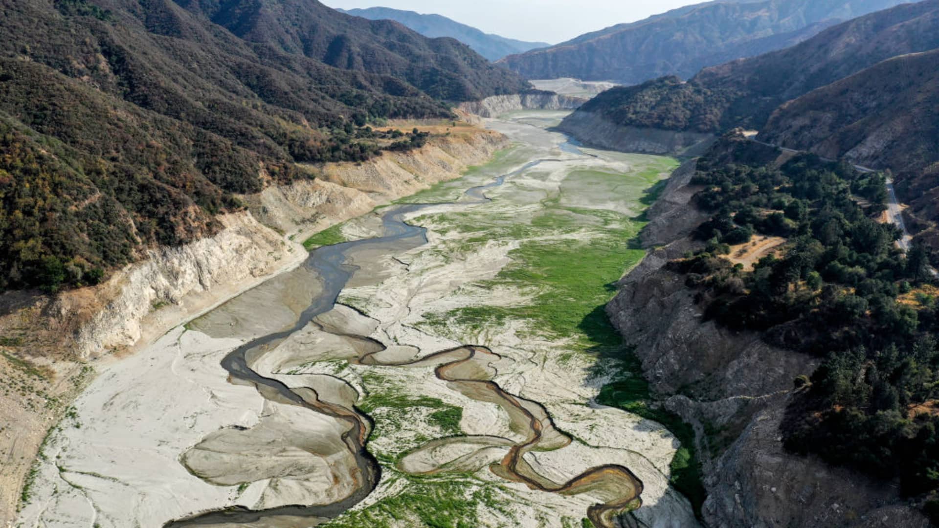 In an aerial view, the San Gabriel River and the exposed lakebed of the San Gabriel Reservoir are seen on June 29, 2021 in the San Gabriel Mountains near Azusa, California.