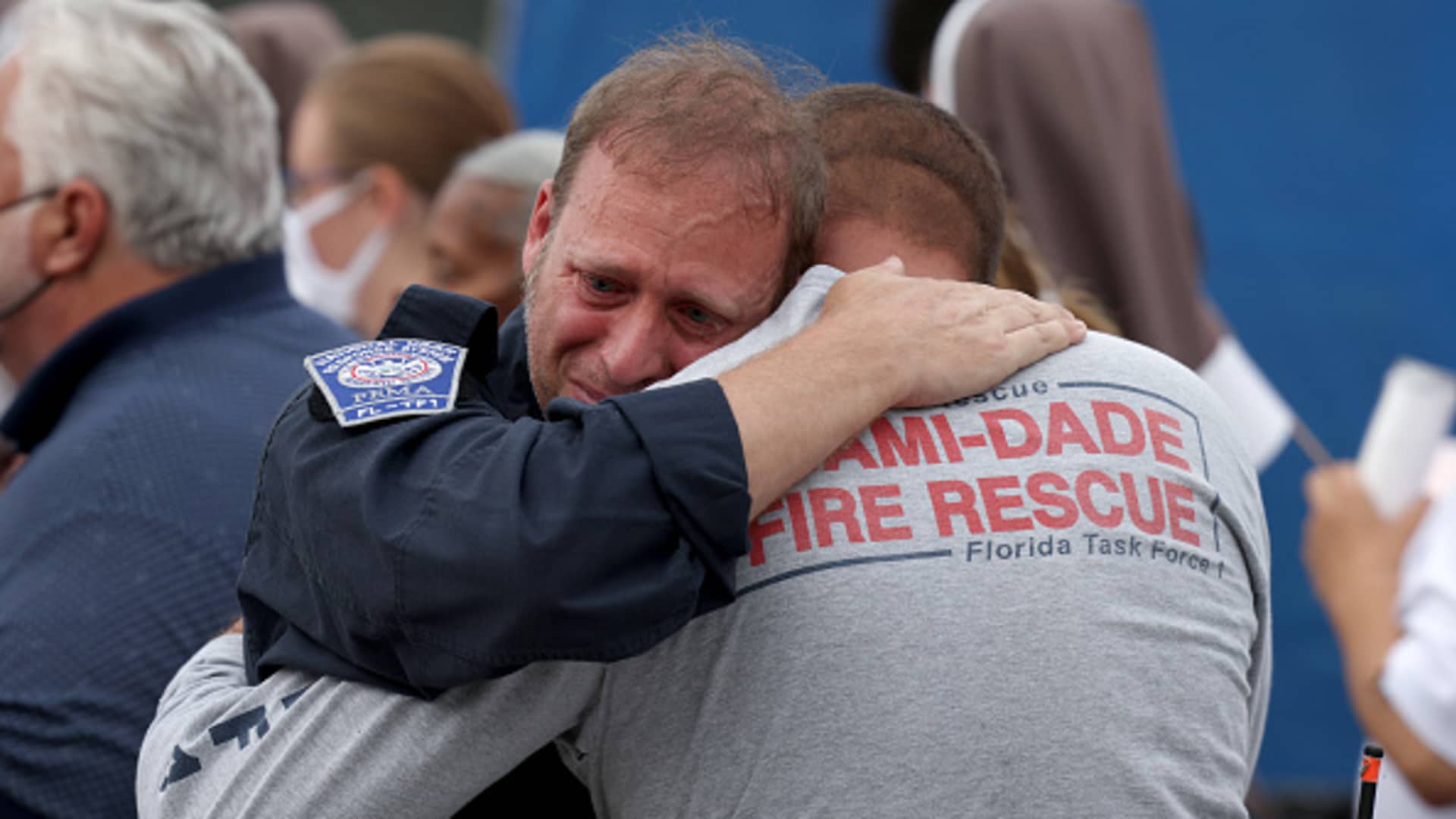 Rescue workers with the Miami Dade Fire Rescue embrace after a moment of silence near the memorial site for victims of the collapsed 12-story Champlain Towers South condo building on July 07, 2021 in Surfside, Florida.