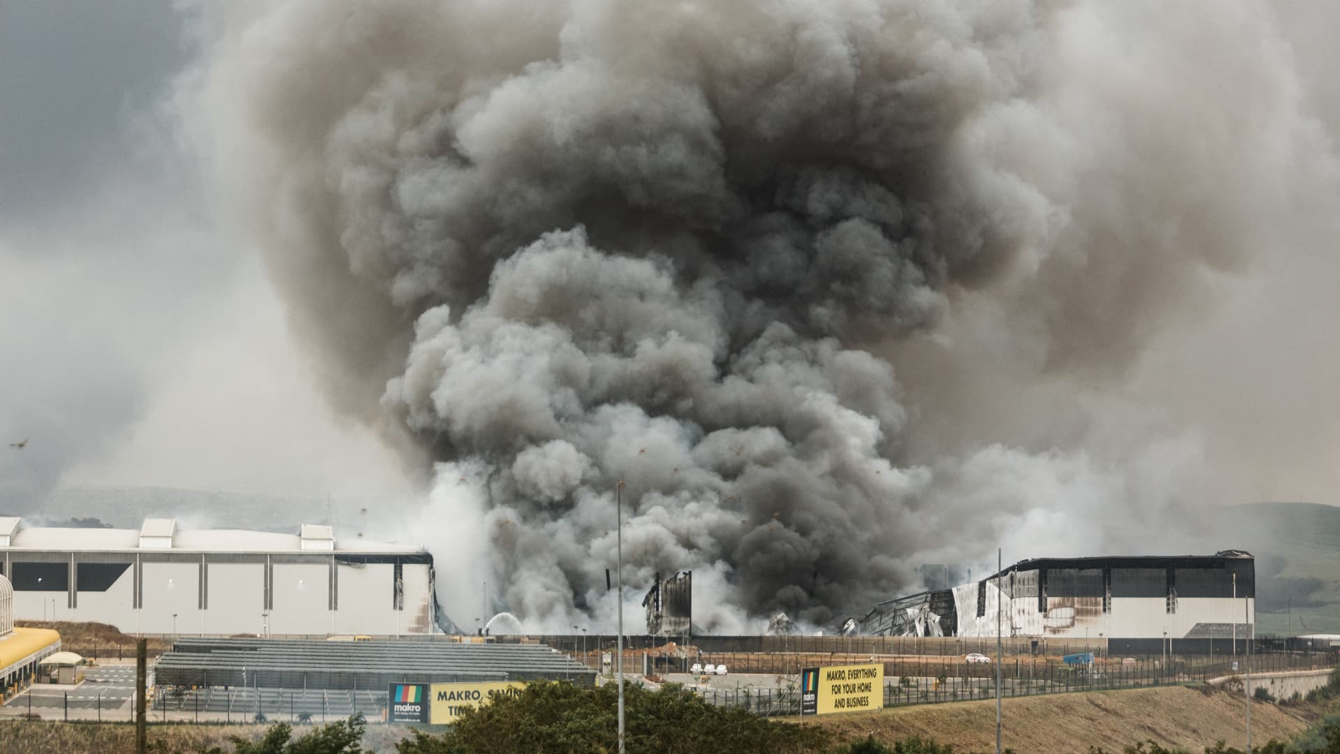 Smoke rises from a Makro building set on fire overnight in Umhlanga, north of Durban, on July 13, 2021 as several shops, businesses and infrastructure are damaged in the city, following four nights of continued violence and looting sparked by the jailing of ex-president Jacob Zuma.