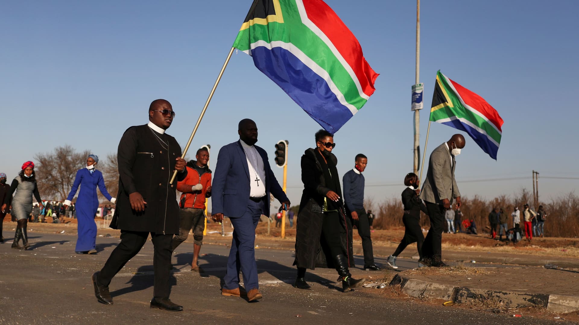 Religious leaders carrying South African flags walk near a looted shopping mall as the country deploys army to quell unrest linked to the jailing of former South African President Jacob Zuma, in Vosloorus, South Africa, July 14, 2021.