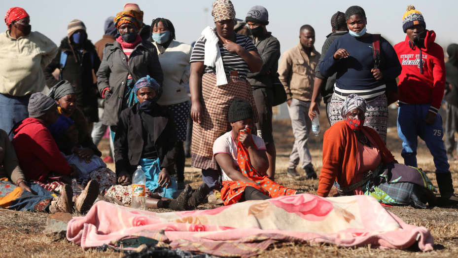 Locals and family members of 15-year-old Vusi Dlamini stand next to his body after he has been allegedly shot outside a mall where looting was taking place, as the country deploys army to quell unrest linked to the jailing of former South African Presiden