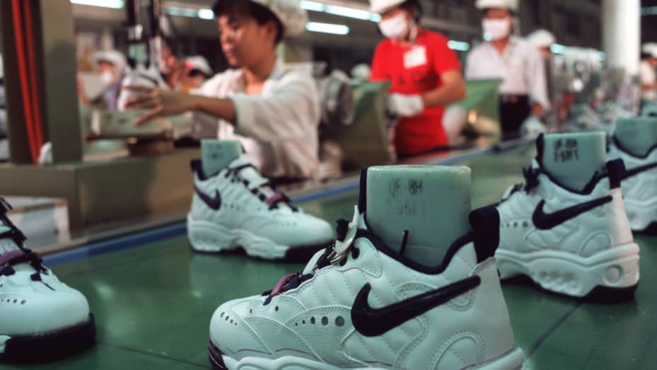Workers in a Nike factory near Ho Chi Minh City work at a production line conveyor belt, putting together Nike sports shoes.
