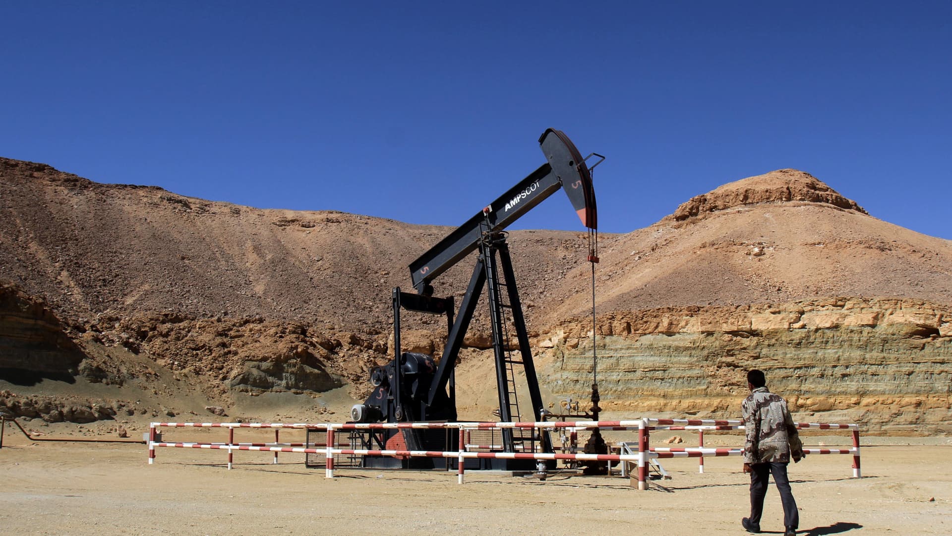 A libyan security member walks by an oil drill on March 23, 2013 at the al-Ghani oil field.
