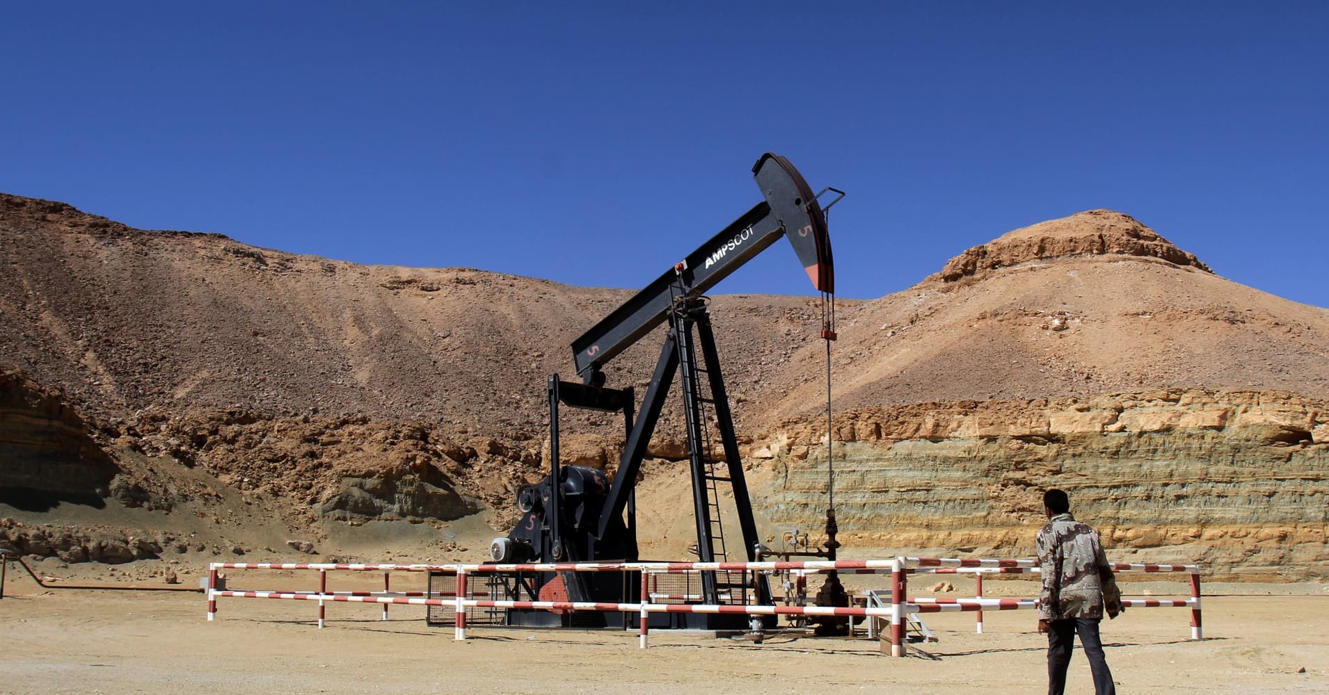 A libyan security member walks by an oil drill on March 23, 2013 at the al-Ghani oil field.