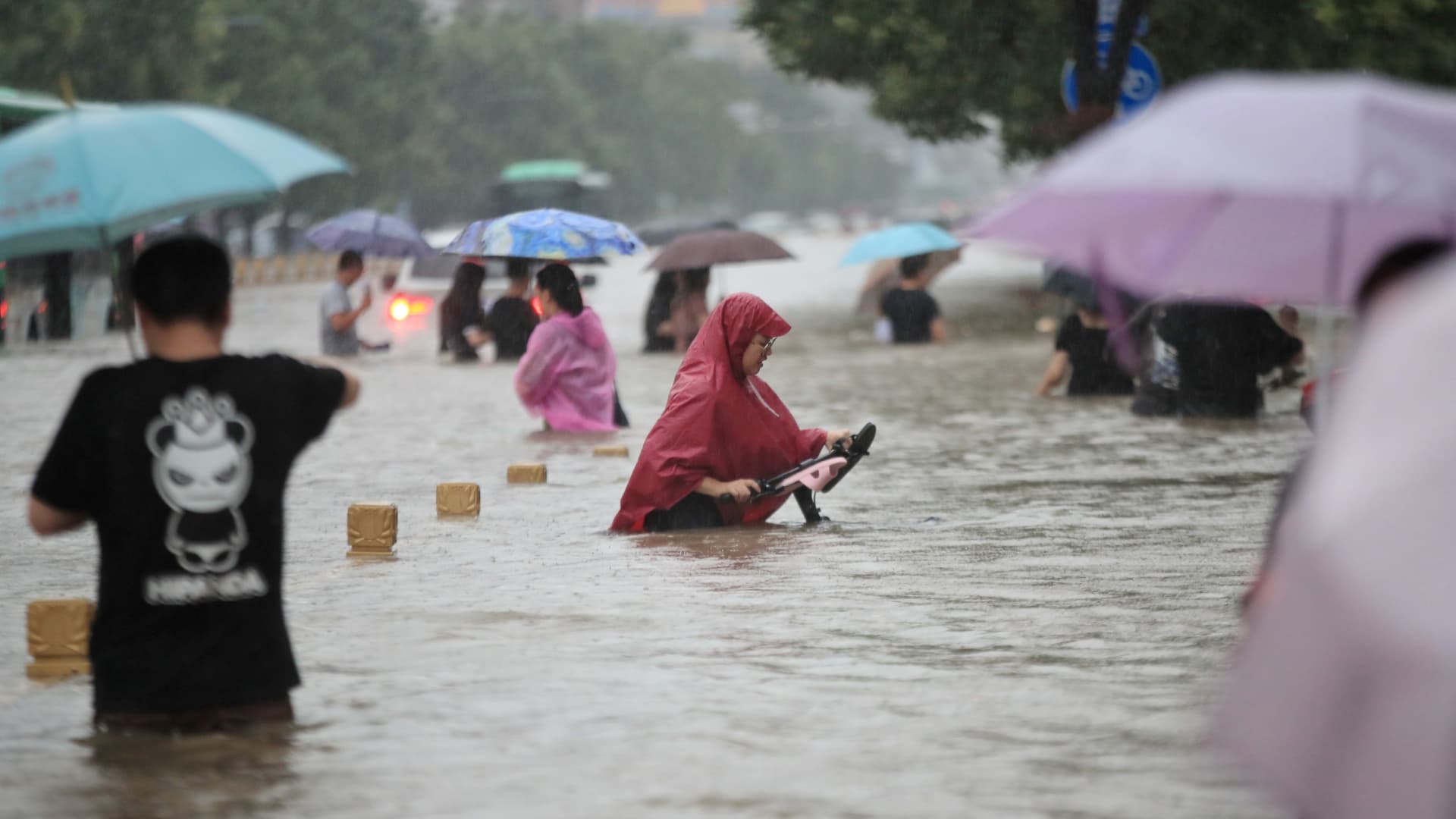 Residents wade through floodwaters on a flooded road amid heavy rainfall in Zhengzhou, Henan province, China July 20, 2021.