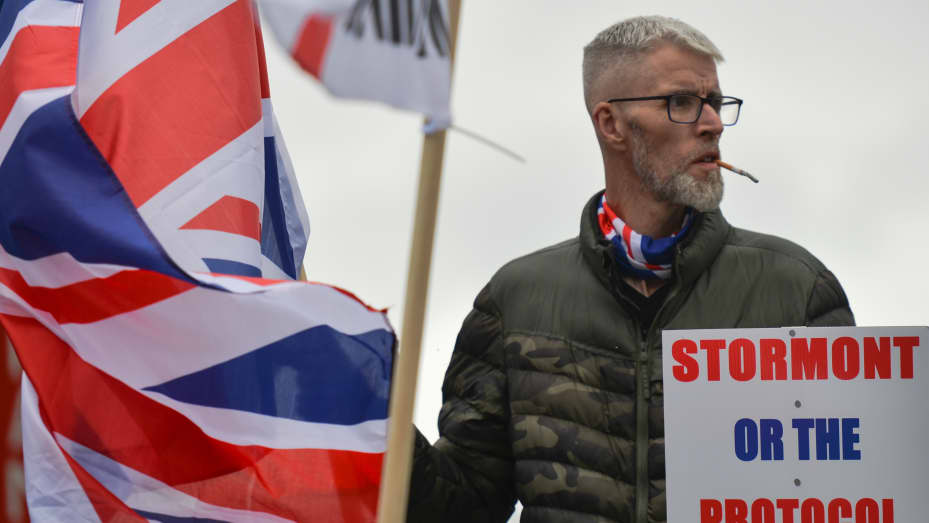 BELFAST, Northern Ireland: A Loyalist holds a placard with words 'Stormont Or The Protocol?' during a protest against the Northern Ireland Protocol at the entrance to Belfast Harbour.