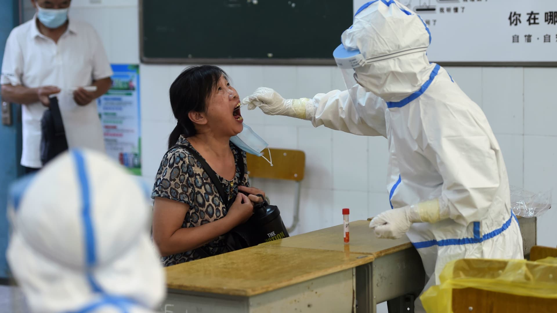 A medical worker in a protective suit collects a swab from a resident during a citywide nucleic acid testing following new cases of the coronavirus disease (COVID-19) in Wuhan, Hubei province, China, August 3, 2021.