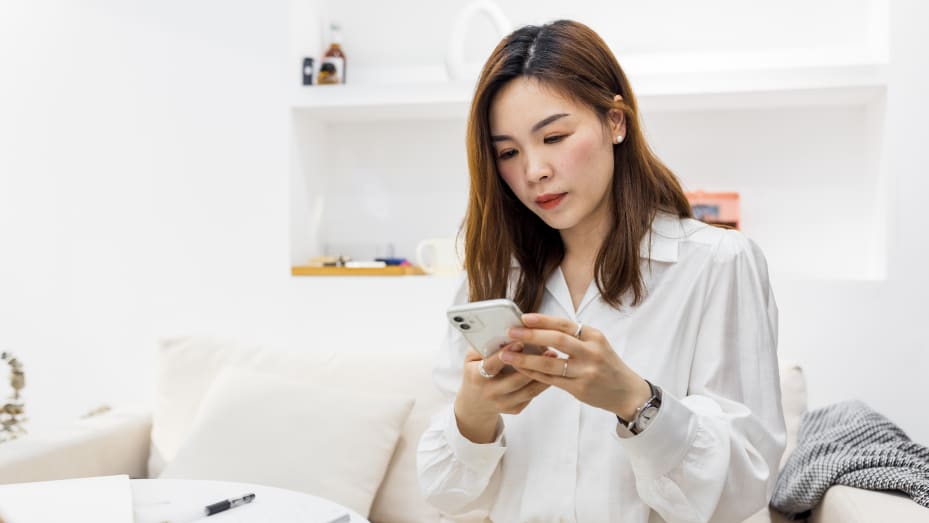 young woman using smartphone to work from home