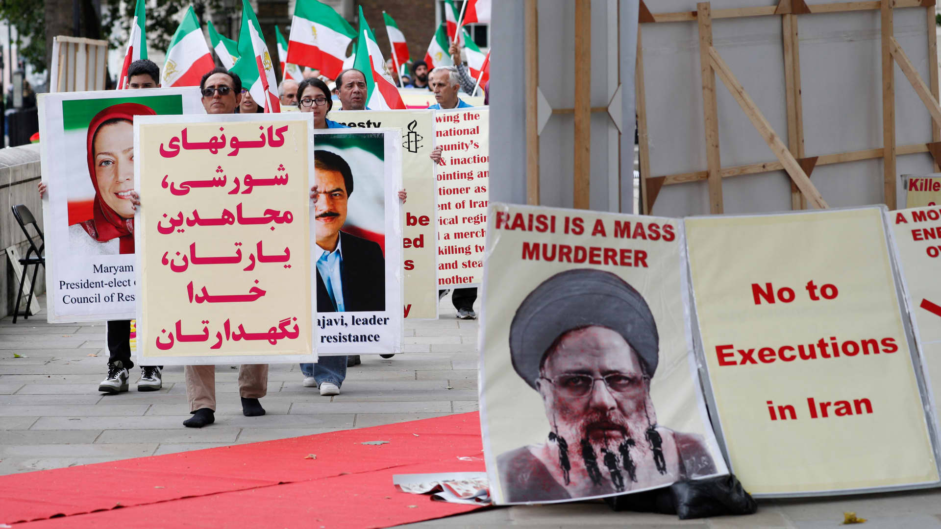 Protesters carry banners during a demonstration organized by supporters of the National Council of Resistance of Iran (NCRI) to protest against the inauguration of Iran's new president Ebrahim Raisi outside Downing Street in central London on August 5, 2021. Raisi is accused of being responsible for the mass execution of thousands of NCRI members in 1988.