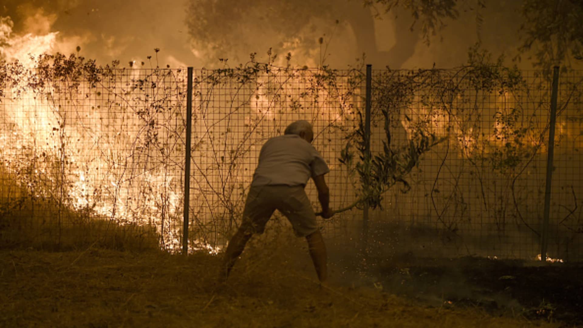 EVIA, GREECE - AUGUST 08: A resident tries to extinguish the fire in the village of Peyki, in the island of Evia on the fifth day of a wildfire on August 08, 2021.