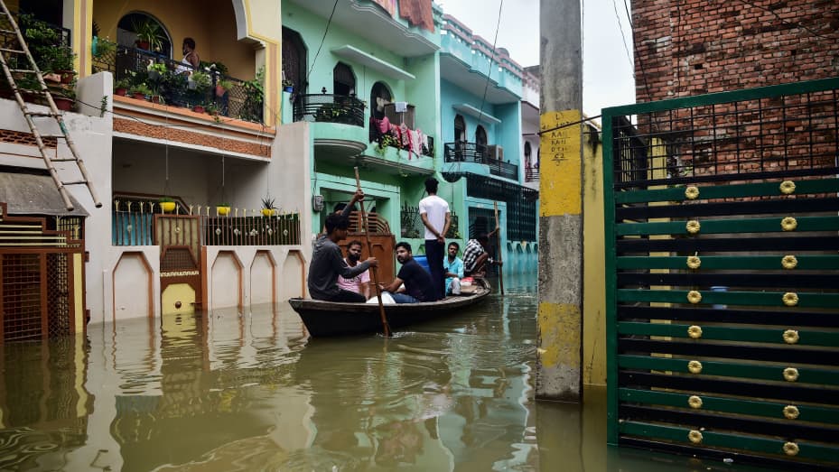 Residents use a boat to move in a flooded neighbourhood in Kareli Gaus Nagar area of Allahabad on August 12, 2021 following heavy monsoon rainfalls that caused the overflowing of the Ganges and Yamuna Rivers.