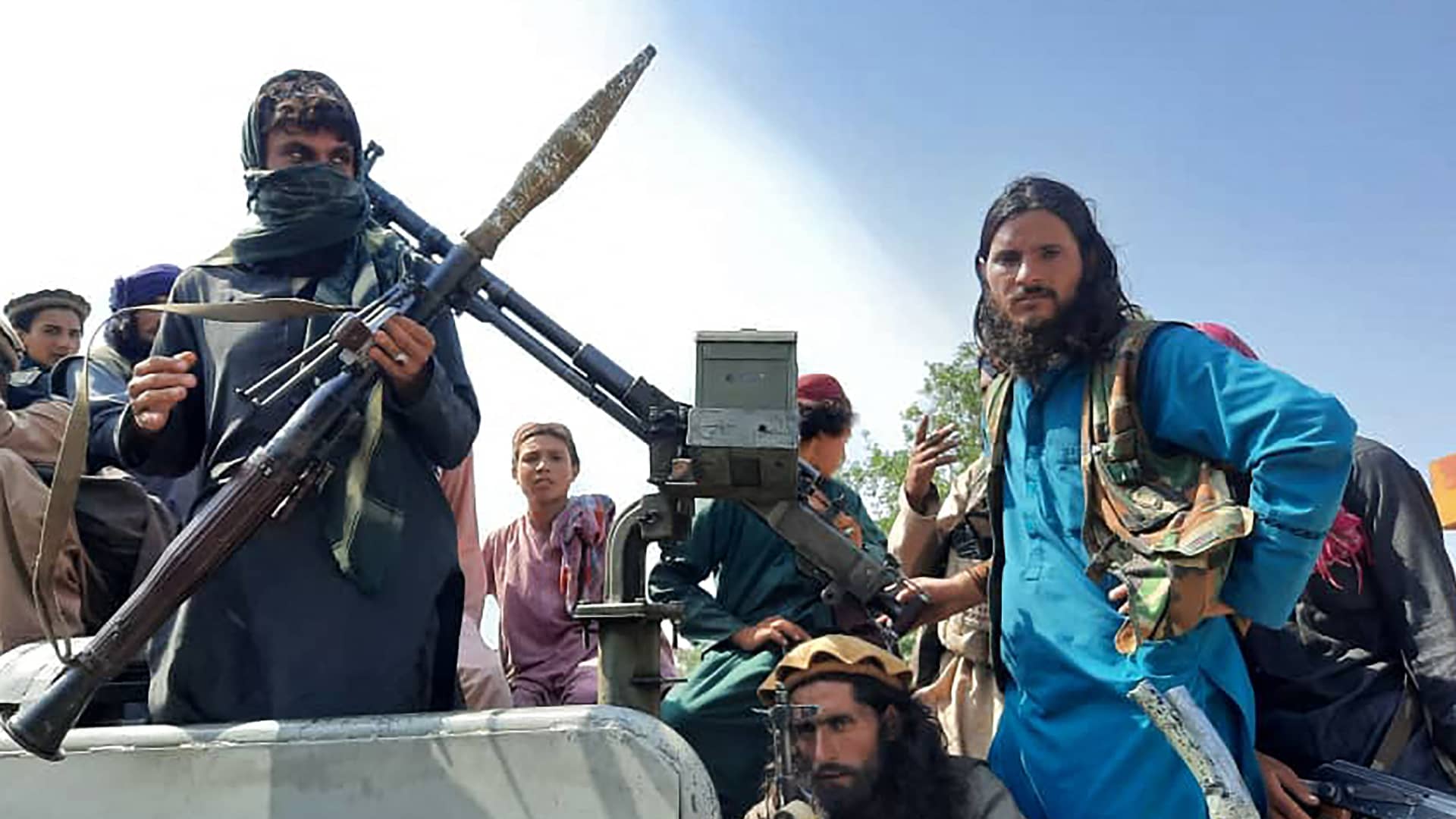 Taliban fighters sit over a vehicle on a street in Laghman province on August 15, 2021.