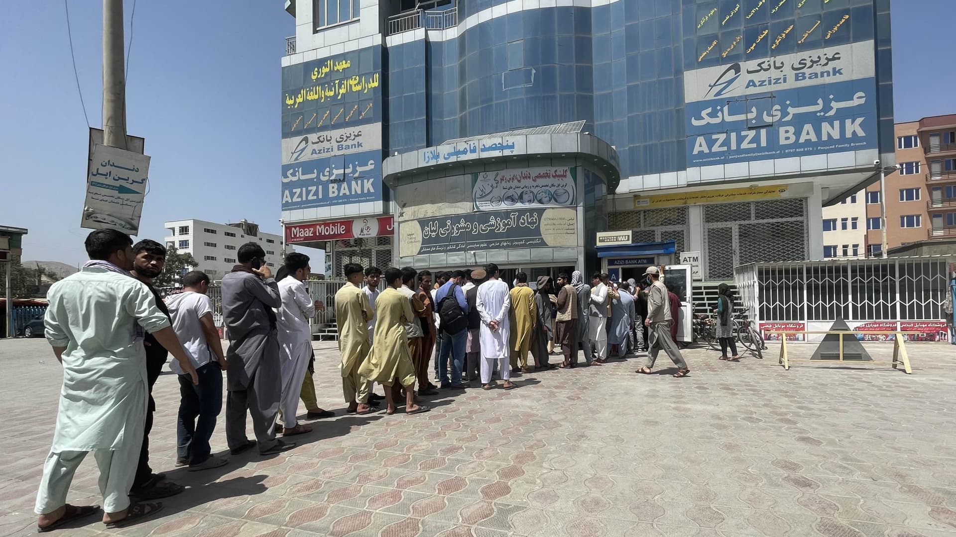 Afghan people line up outside AZIZI Bank to take out cash as the Bank suffers amid money crises in Kabul, Afghanistan, on August 15, 2021.