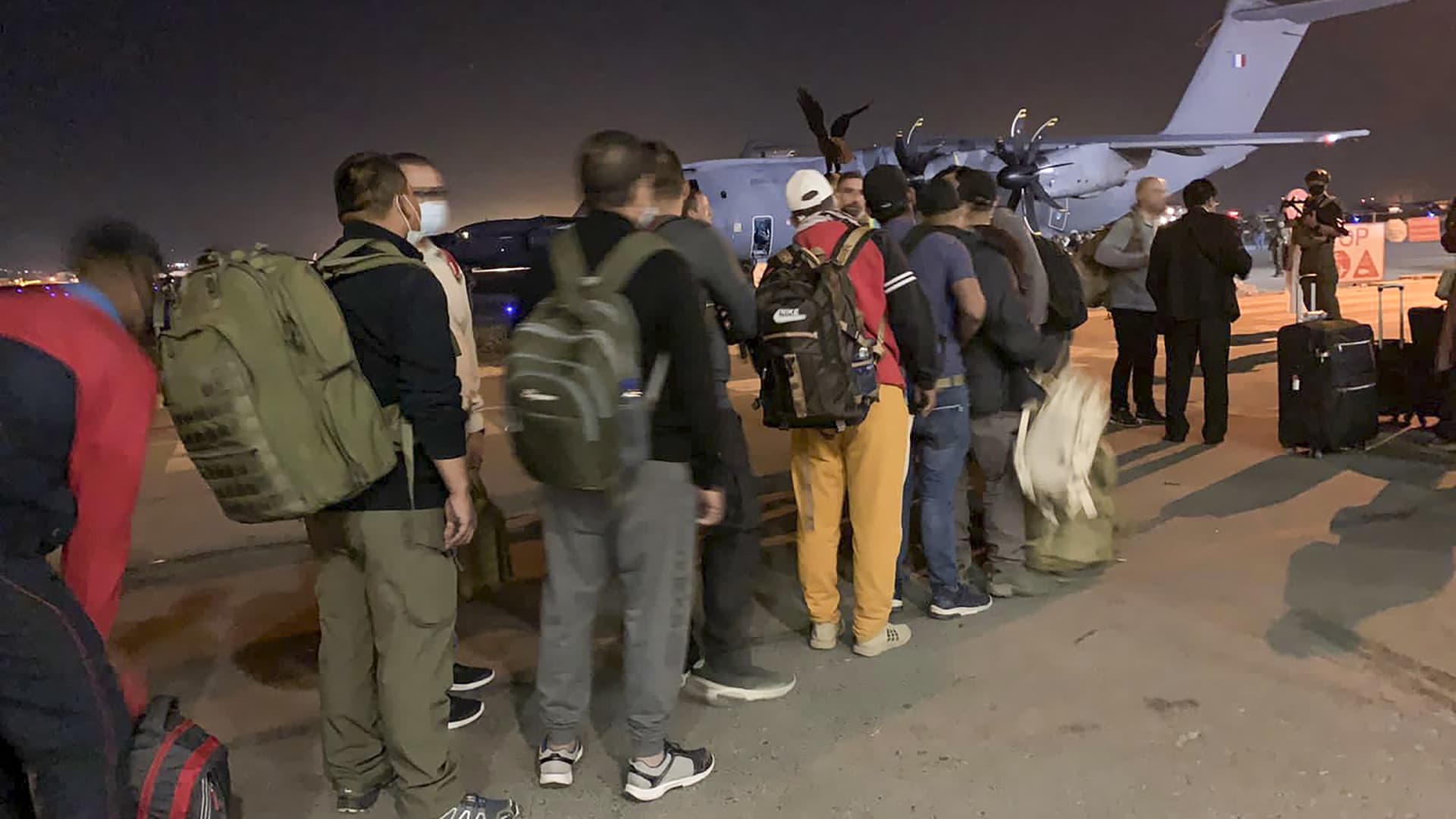 French and Afghan nationals line up to board a French military transport plane at the Kabul airport on August 17, 2021, for evacuation from Afghanistan after the Taliban's stunning military takeover of the country. (Photo by STR / AFP) (Photo by STR/AFP via Getty Images)