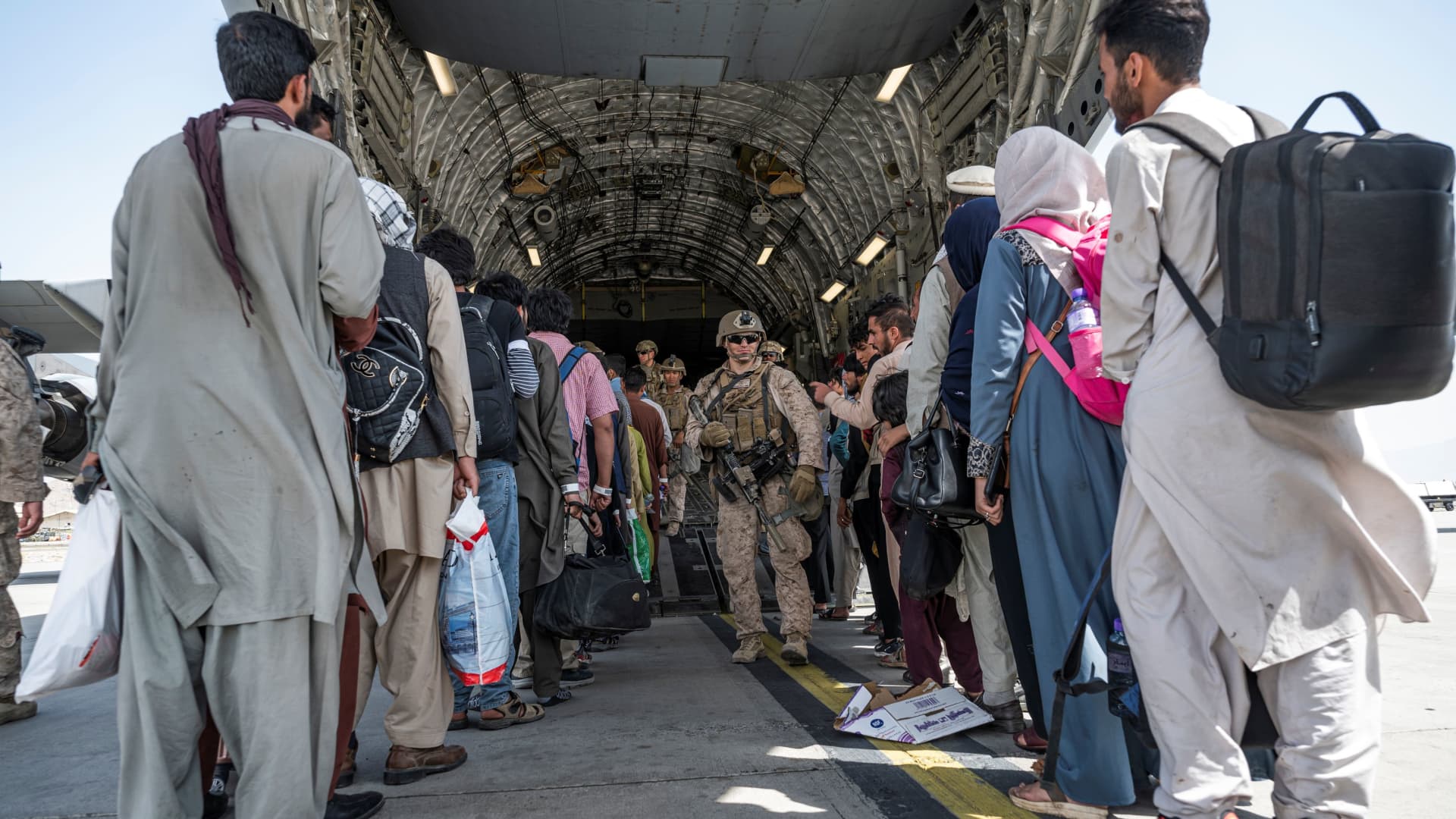 U.S. Airmen and U.S. Marines guide qualified evacuees aboard a U.S. Air Force C-17 Globemaster III at Hamid Karzai International Airport (HKIA), Afghanistan, August 21, 2021.