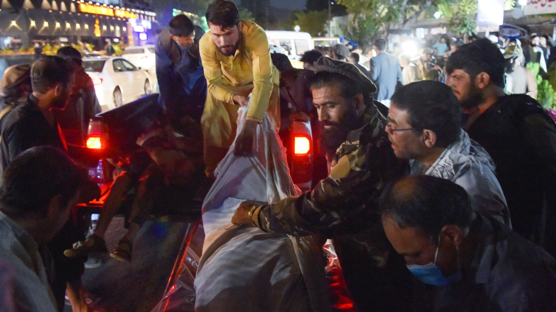 Warning: Graphic image. Volunteers and medical staff unload bodies from a pickup truck outside a hospital after two powerful explosions, which killed at least six people, outside the airport in Kabul on August 26, 2021.