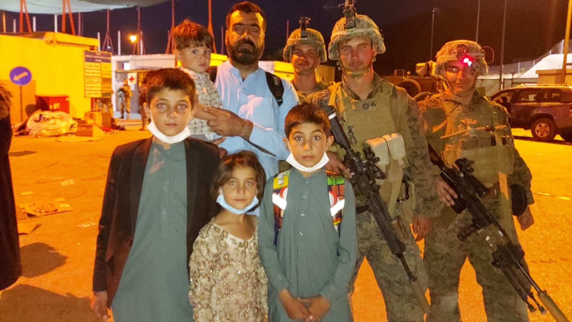 Antifullah Ahmadzai, a former Afghan interpreter for the U.S. military, stands with his children and U.S. Marines at Hamid Karzai International Airport in Kabul, Afghanistan.