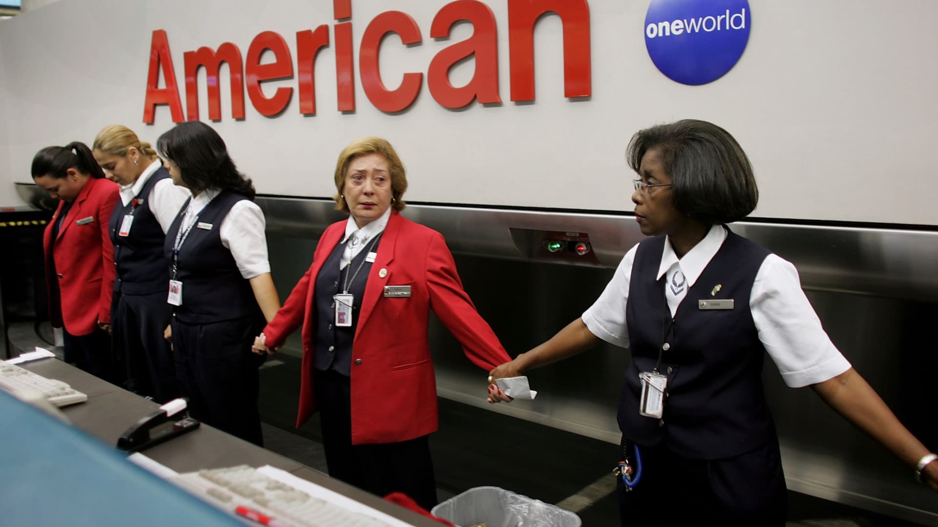 American Airlines employee Tamara Ronquillo (2nd-R) holds hands with her colleagues as they observe a moment of silence on the 5th anniversary of the September 11 terrorist attacks September 11, 2006 at the Miami International Airport in Miami, Florida.