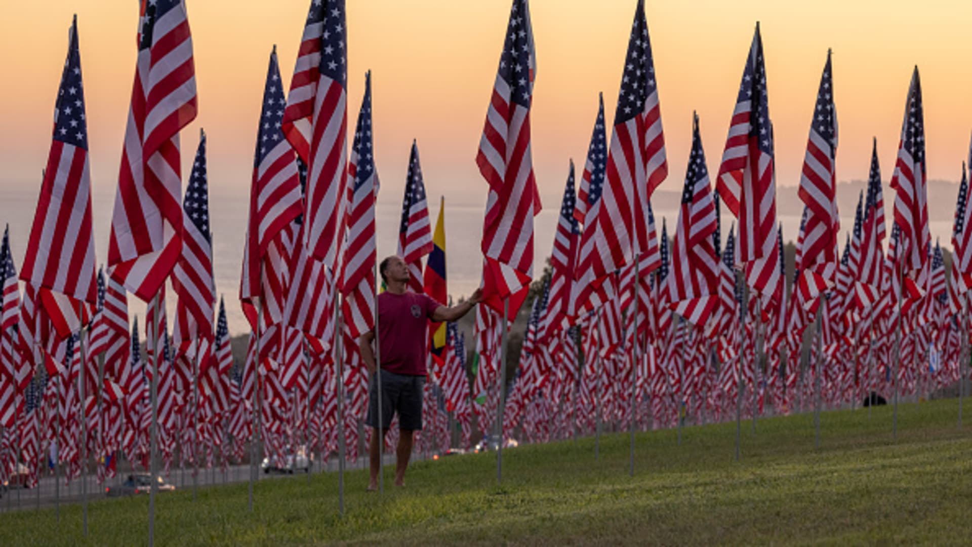 A man touches a flag during the 14th annual Waves of Flags on the eve of the 20th anniversary of the September 11 terror attacks in Alumni Park at Pepperdine University on September 10, 2021 in Malibu, California.