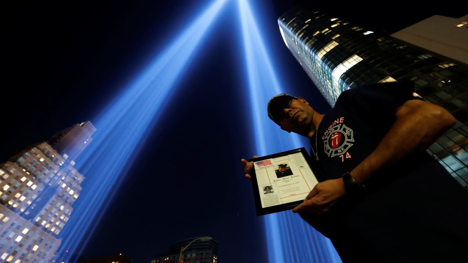 Sergeant Edwin Morales holds a photo of his cousin Rubin Correa from Engine 74 by the Tribute in Light installation ahead of the 20th anniversary of the September 11 attacks in New York City, U.S., September 10, 2021.