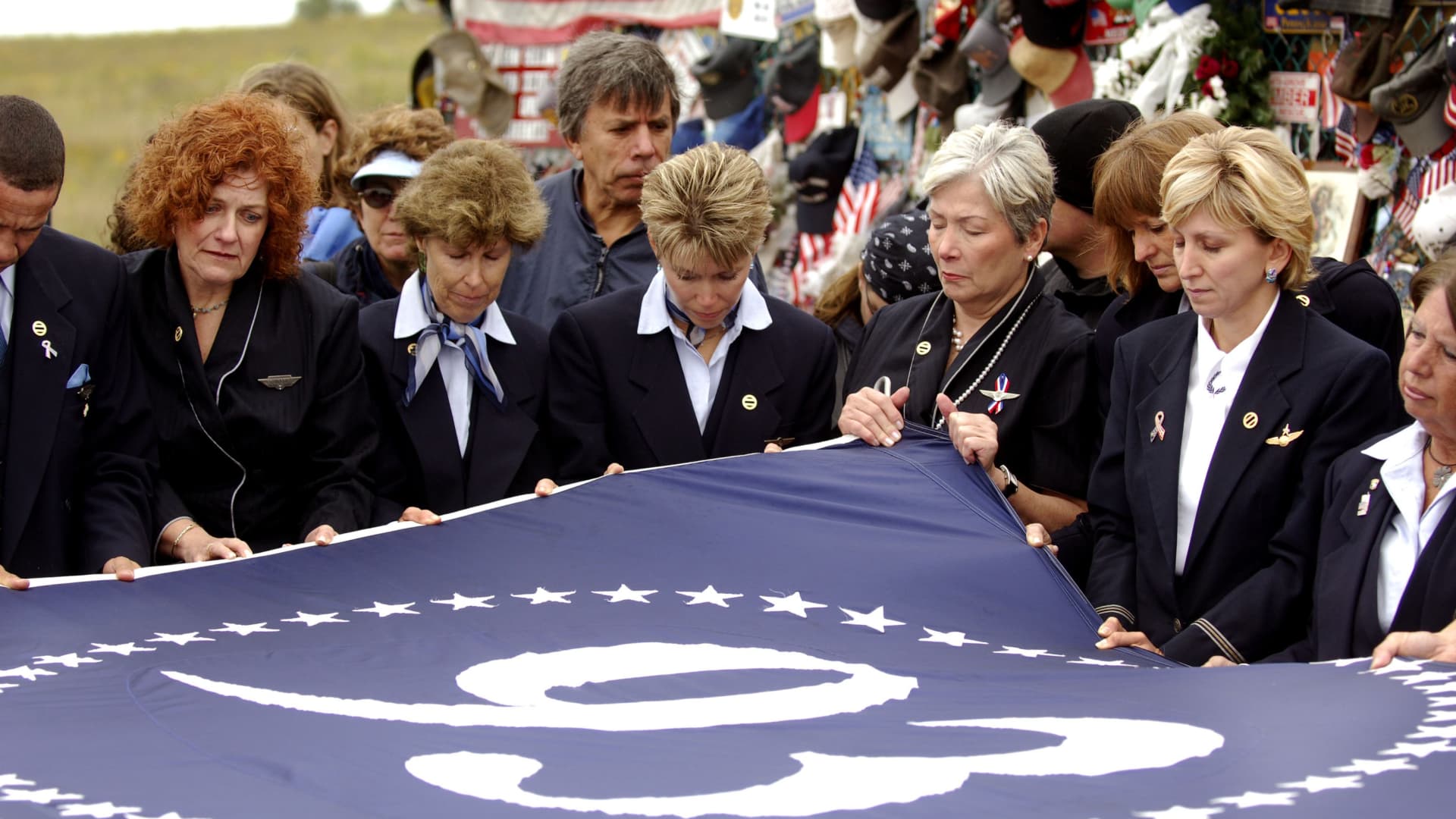 United Airlines flight attendants unfold a flag at a memorial site on the 5th anniversary of the September 11, 2001 attacks, where United Flight 93 crashed into a field in Shanksville, Pennsylvania, September 11, 2006.