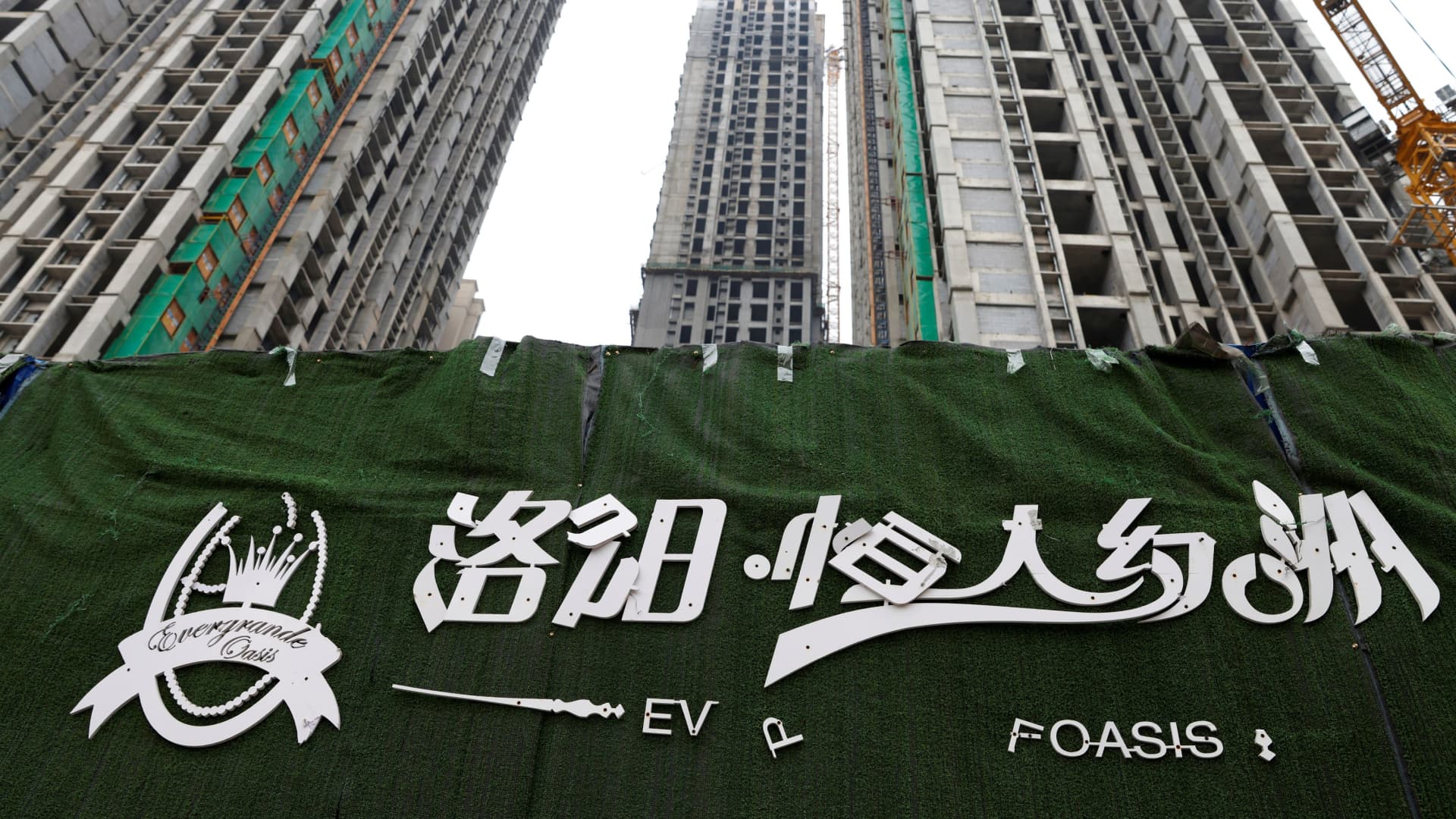 A peeling logo of the Evergrande Oasis, a housing complex developed by Evergrande Group, is pictured outside the construction site where the residential buildings stand unfinished, in Luoyang, China September 16, 2021. Picture taken September 16, 2021.
