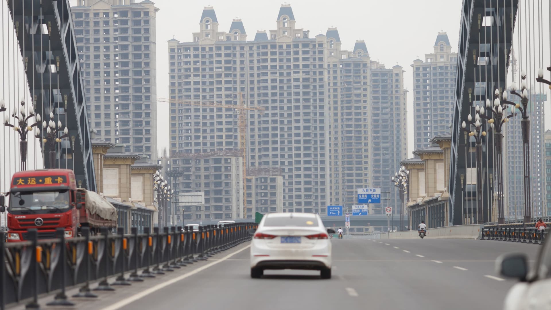 Vehicles drive near unfinished residential buildings from the Evergrande Oasis, a housing complex developed by Evergrande Group, in Luoyang, China September 16, 2021.