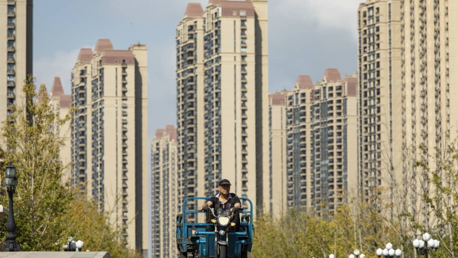 Un hombre conduce un carro junto a edificios de apartamentos en el desarrollo inmobiliario y turístico Life in Venice de China Evergrande Group en Qidong, provincia de Jiangsu, China, el martes 21 de septiembre de 2021.