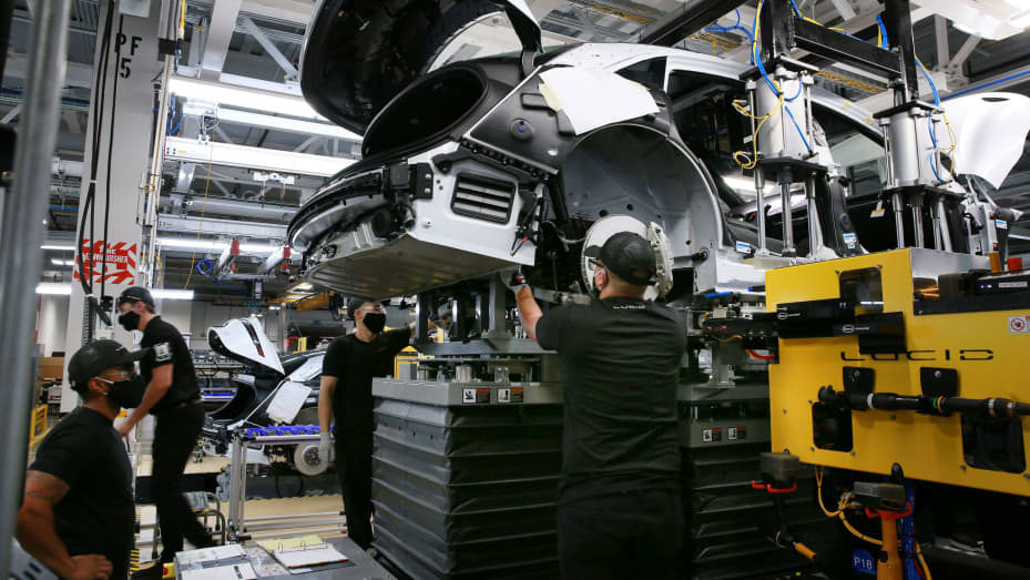 Workers marry the body structure with the battery pack and the front and rear sub frames as they assemble electric vehicles at the Lucid Motors plant in Casa Grande, Arizona, September 28, 2021.