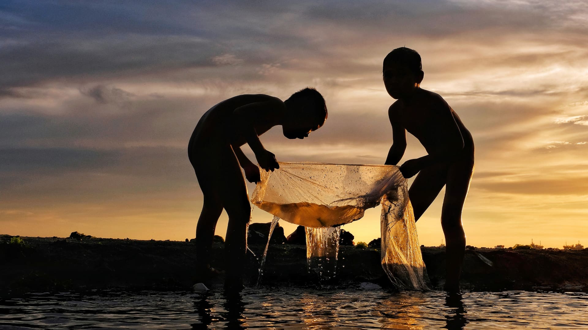 Two boys fish against the sunset sky in Zamboanga, Philippines.