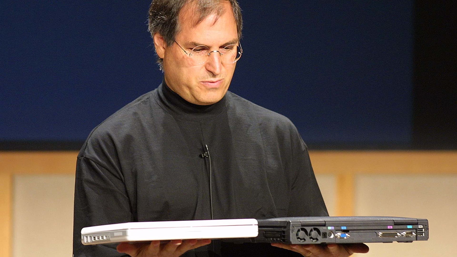 Steve Jobs compares the weight of the iBook notebook computer weighing4.9 pounds (L) and a Dell computer notebook during a Apple Media event in Cupertino, California 01 May 2001.