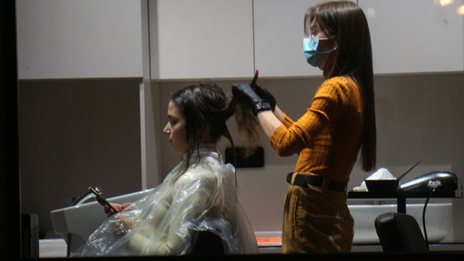A hairdresser wearing protective face mask and gloves styles a clients's hair on October 6, 2021 in Moscow, Russia.