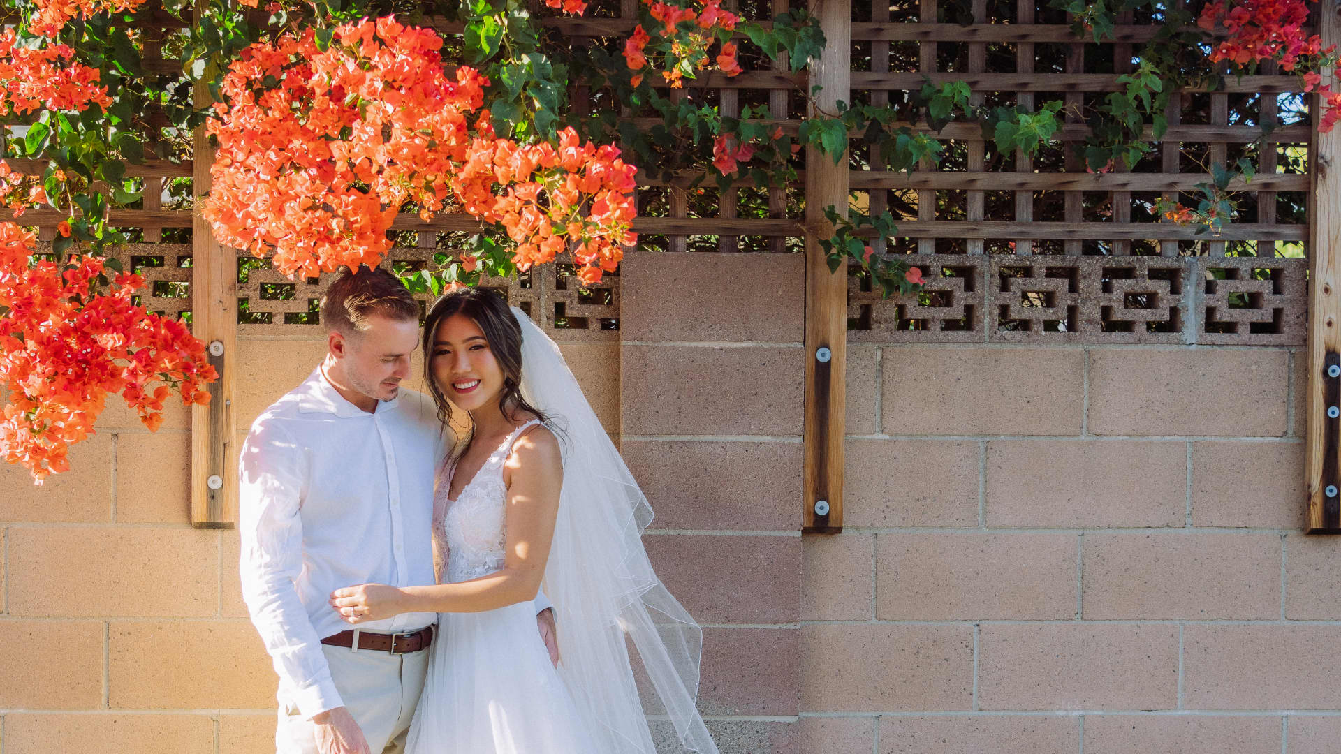 Kim Liao and her husband in front of a flower wall she handmade for her wedding.