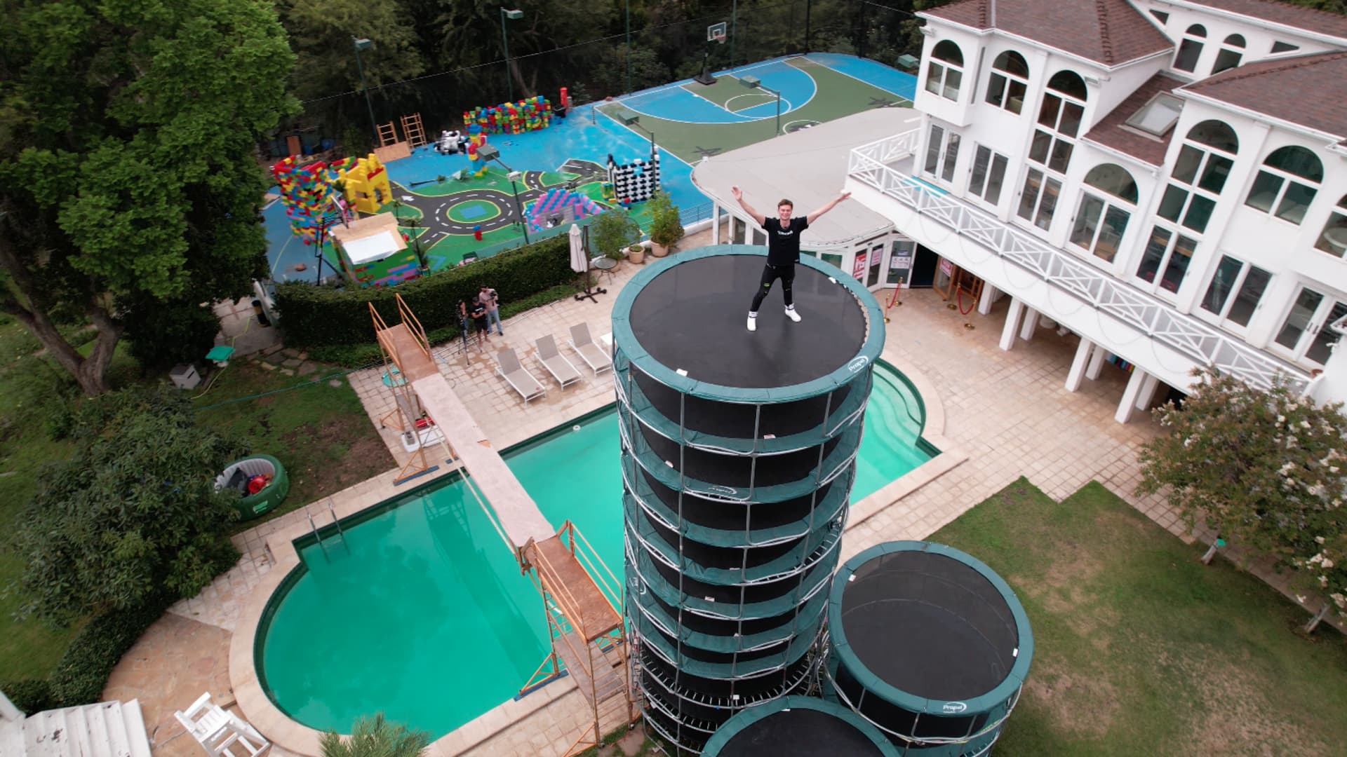 Carter Sharer standing on a stack of trampolines outside the YouTube group Team RAR's rental home.