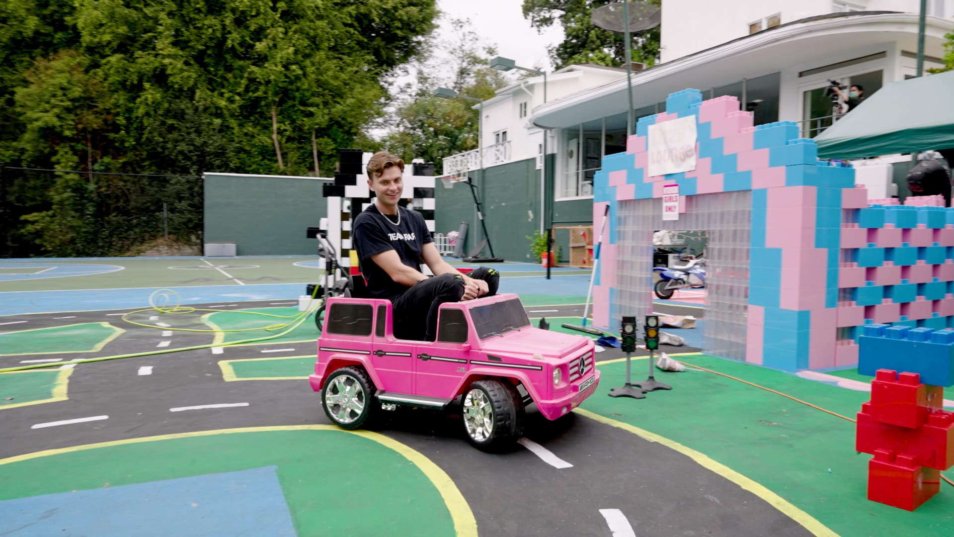 Sharer drives a miniature go-kart on their tennis court, which was converted into a life-sized LEGO World for a recent video.