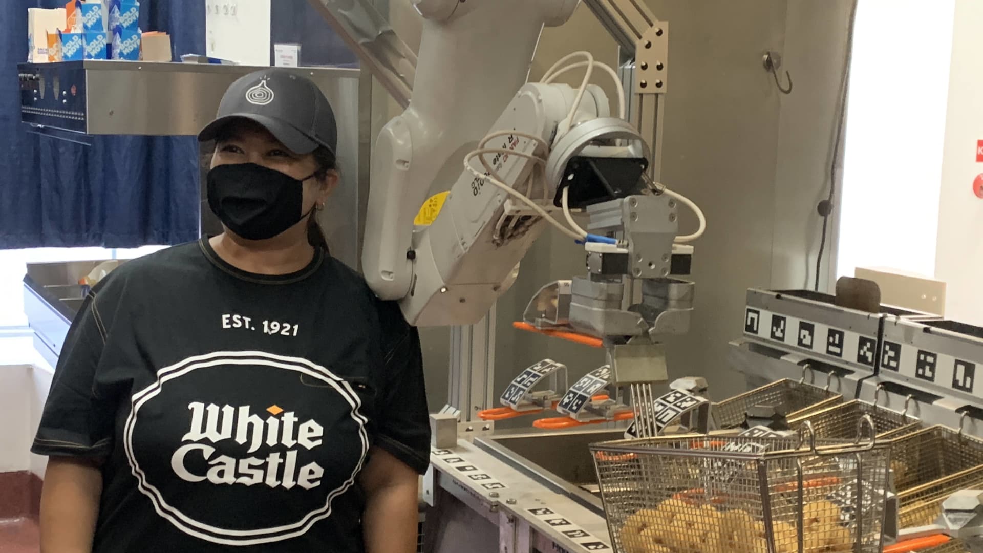 A White Castle team member next to Miso Robotics' Flippy.