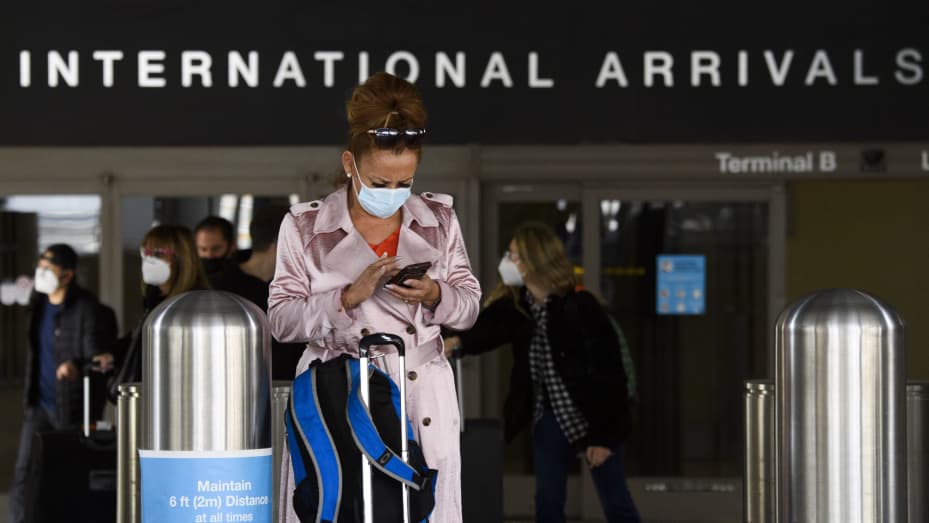 A traveler wears a face mask while checking their phone on the arrivals level outside the Tom Bradley International Terminal (TBIT) at Los Angeles International Airport (LAX) amid increased Covid-19 travel restrictions on January 25, 2021 in Los Angeles,