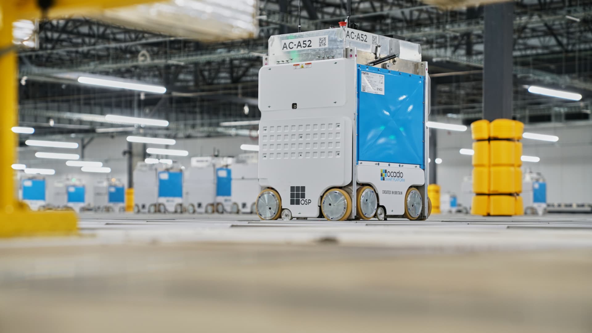 Robots glide on top of a grid and help retrieve groceries in Kroger's automated warehouses. The robots are powered by software from U.K.-based Ocado.