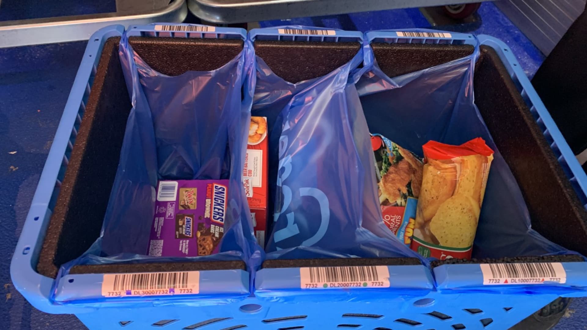 Groceries are picked by employees and put into bags inside of plastic totes. The totes are color-coded.