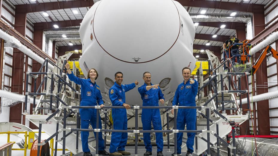The SpaceX Crew-3 astronauts stand on the transporter in front of the Crew Dragon and Falcon 9 stack inside the SpaceX horizontal processing facility at Kennedy Space Center in Florida on Oct. 26, 2021.